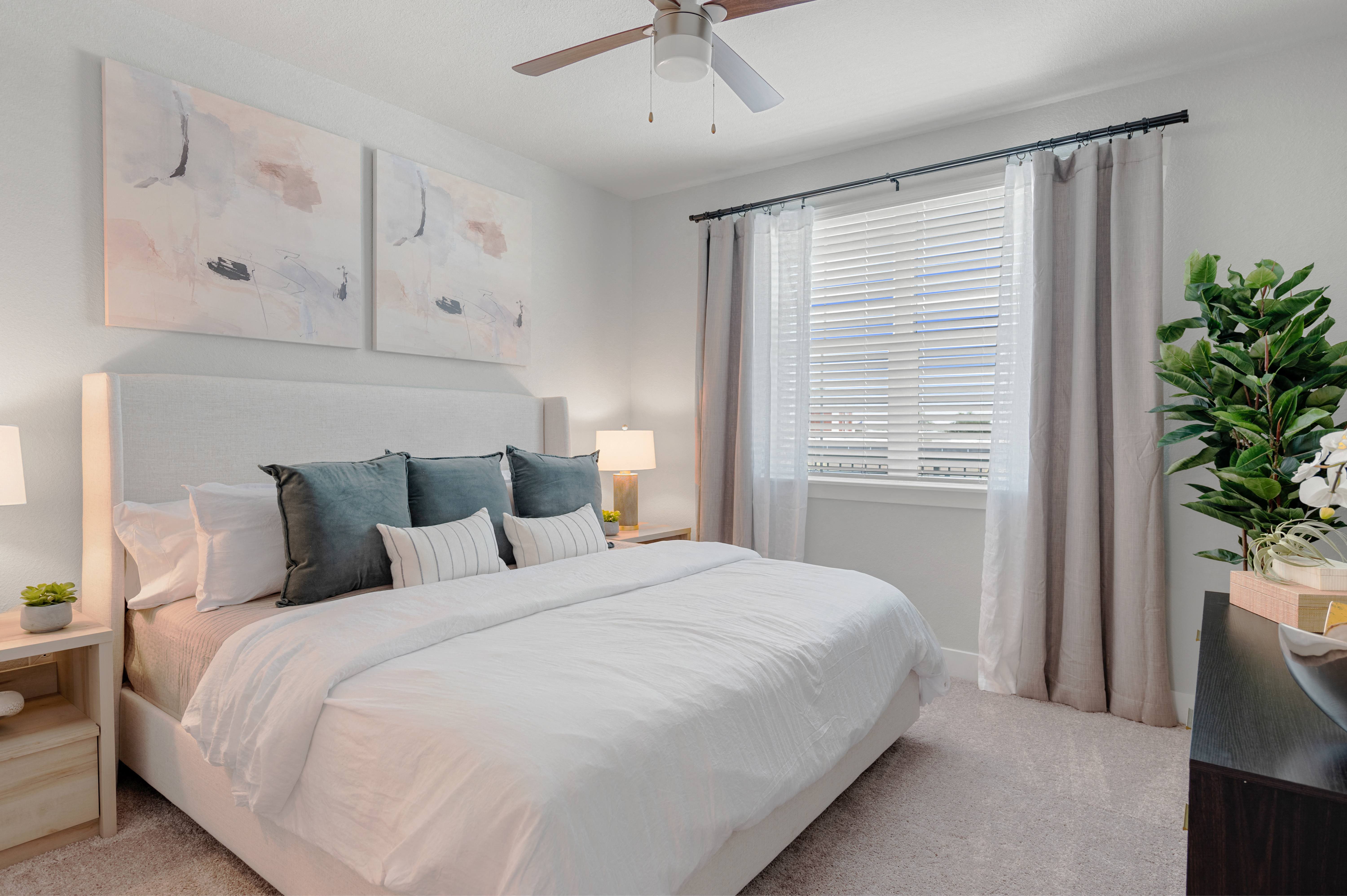 a bedroom with a large white bed and a ceiling fan